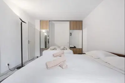 a white bedroom with two beds with towels on them at Branly in Cannes