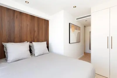 a bedroom with a white bed and a wooden headboard at Quartier Marriott - Superbe 3 pieces in Cannes