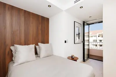 a bedroom with a white bed with a wooden headboard at Quartier Marriott - Superbe 3 pieces in Cannes