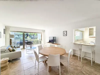 a living room with a table and chairs and a kitchen at 86m2, spacieux, 2 chambres, à 1 min de la plage in Cannes