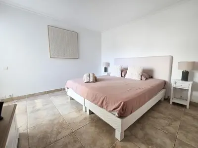a bed in a white room with a white wall at 86m2, spacieux, 2 chambres, à 1 min de la plage in Cannes