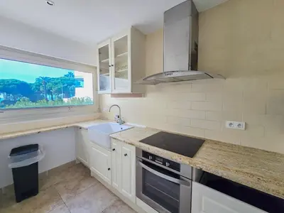 a kitchen with white cabinets and a sink and a window at 86m2, spacieux, 2 chambres, à 1 min de la plage in Cannes