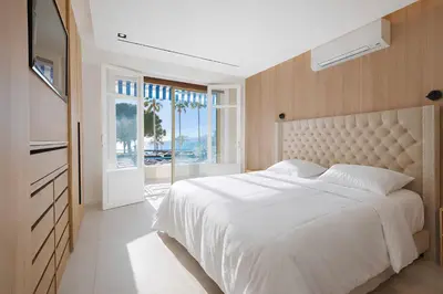 a bedroom with a large white bed and a window at Celestre Croisette - Appartement de Luxe Croisette avec Terrasse et Vue Mer in Cannes