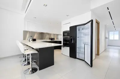 a kitchen with a black refrigerator and white cabinets at Sable Croisette - Appartement de Luxe avec terrasse et vue Mer in Cannes