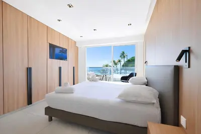 a bedroom with a large bed with a view of the ocean at Reflet Croisette - Luxury Apartment with Terrace and Sea View in Cannes