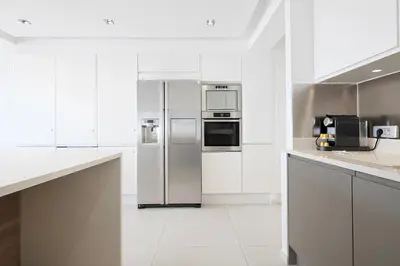 a kitchen with white cabinets and stainless steel appliances at Reflet Croisette - Luxury Apartment with Terrace and Sea View in Cannes