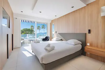 a bedroom with a large bed with a view of the ocean at Reflet Croisette - Luxury Apartment with Terrace and Sea View in Cannes
