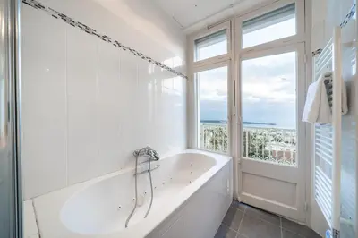 a white bathroom with a tub and a window at COZYSTAY Elegant Two-Bedroom Apartment in the 