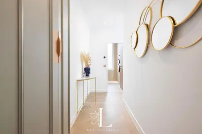 a hallway with white walls and gold chandeliers at Les Lucioles 2 - Appartement Luxe Studio Balcon in Cannes