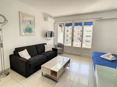 a living room with a black couch and a table at Appartements Medicis in Cannes