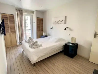 a bedroom with a large white bed and a window at Appartements Medicis in Cannes
