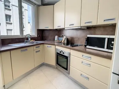 a kitchen with white cabinets and a sink and a microwave at Appartements Cannes Centre : Rond Point Duboys d'Angers in Cannes