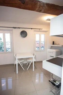 a white kitchen with a table and two windows at Cannes Marina by Connexion in Cannes