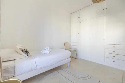 a white bedroom with a bed and a chair at Splendid apartment a-c 2BR-4P - Sea View in Cannes