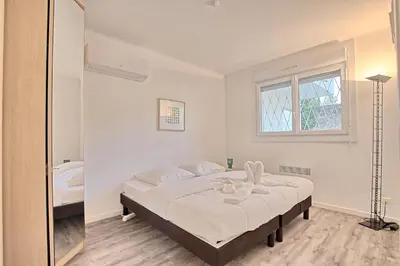 a bedroom with a large bed with a mirror at Appartement Vallombrosa proche Plages et Palais in Cannes