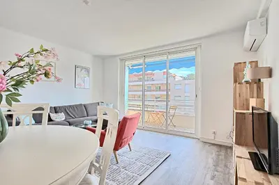 a living room with a table and a window at Appartement Vallombrosa proche Plages et Palais in Cannes