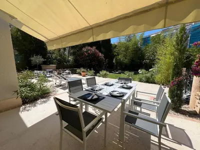 a table and chairs under an umbrella on a patio at Elegant 3-BR Cannes Garden Condo - 5 Min Walk to Beach - behind Martinez in Cannes