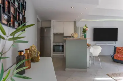 a living room with a kitchen with a counter and a tv at Louison balcony, quiet area, 7mn from beach in Cannes