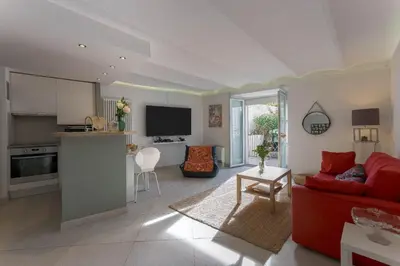 a living room with a red couch and a kitchen at Louison balcony, quiet area, 7mn from beach in Cannes