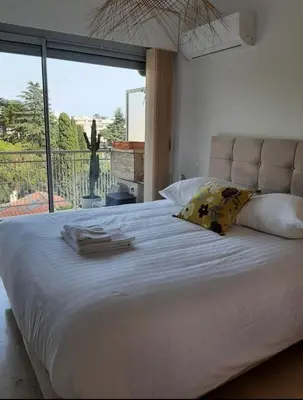 a bedroom with a large white bed with a large window at Appartement Ima in Cannes