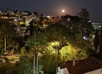 a view of a city at night with a full moon at Appartement Ima in Cannes