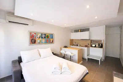 a bedroom with a white bed and a kitchen at Le Palm - Croisette - Beach - Casino - Wi-Fi in Cannes