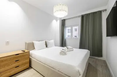 a small bedroom with a bed and a chandelier at Luxury apt 5 min from the beach and La Croisette in Cannes