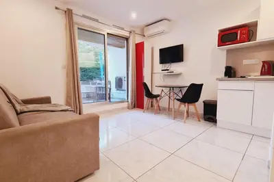 a living room with a couch and a table with chairs at Charming studio with terrace in Cannes