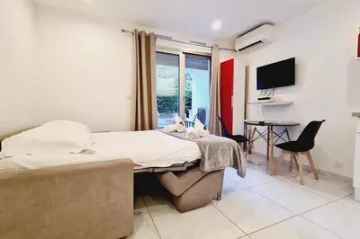 a bedroom with a bed and a desk and a television at Charming studio with terrace in Cannes