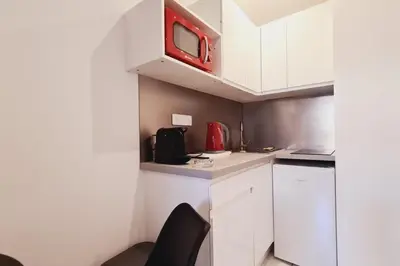 a small kitchen with white cabinets and a red microwave at Charming studio with terrace in Cannes