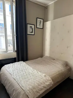 a bed in a bedroom with two pictures on the wall at Appartement moderne et chaleureux à 2 minutes du Palais in Cannes