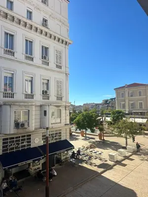 a large white building with a blue awning in front of it at Appartement moderne et chaleureux à 2 minutes du Palais in Cannes
