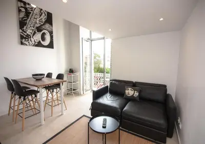 a living room with a black leather couch and a table at Sunny Duplex by Connexion in Cannes
