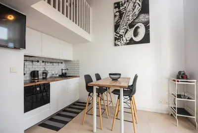 a kitchen with white cabinets and a wooden table at Sunny Duplex by Connexion in Cannes
