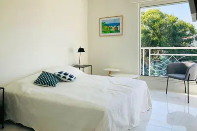 a white bedroom with a bed and a large window at Sea view apartment-3 pers-with pool-Cannes in Cannes