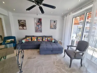 a living room with a blue couch and a ceiling fan at Velasquez Martinez Plage in Cannes