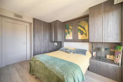 a bedroom with a large bed with wooden cabinets at FRGK Air-Conditioned Duplex with Terrace Secure Residence & Premium Amenities in Cannes
