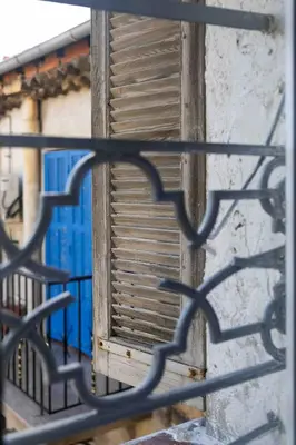 a window with a wooden shutter behind a metal fence at Charme au Suquet 1 Chambre & Canapé-Lit AC in Cannes