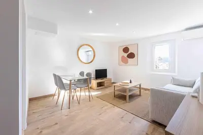 a white living room with a table and a couch at Charme au Suquet 1 Chambre & Canapé-Lit AC in Cannes