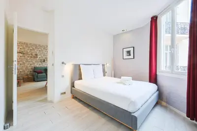 a bedroom with a large white bed with a red curtain at Hyper centre spacieux & lumineux proche Palais in Cannes