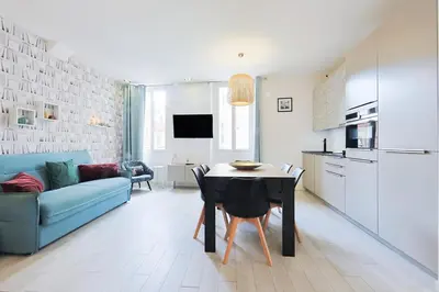 a kitchen and living room with a table and a blue couch at Hyper centre spacieux & lumineux proche Palais in Cannes