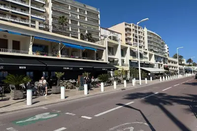 a street with tables and chairs and a building at One-bedroom apt ideally located in front of the Midi beaches in Cannes