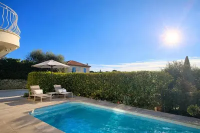 a swimming pool with two chairs and an umbrella at Private Pool House , 10min Cannes in Le Cannet