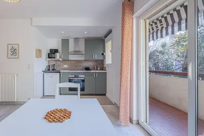 a kitchen with a white table and a large window at Studio avec balcon et parking proche plages in Cannes