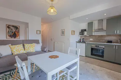 a living room with a couch and a table and a kitchen at Studio avec balcon et parking proche plages in Cannes