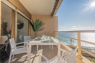 a white dining table and chairs on a balcony at Elégant 2 pièces - accès mer direct vue splendide in Cannes