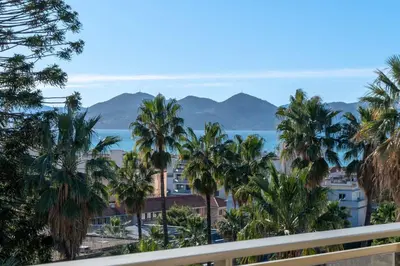 a view from the balcony of a resort with palm trees at 104 sqm Sea-View Apartment Cannes in Cannes
