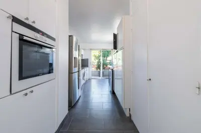 a hallway with a kitchen with white cabinets and a television at 104 sqm Sea-View Apartment Cannes in Cannes