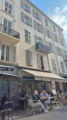 a group of people sitting at tables in front of a building at Charming one-bedroom flat on rue Hoche in Cannes