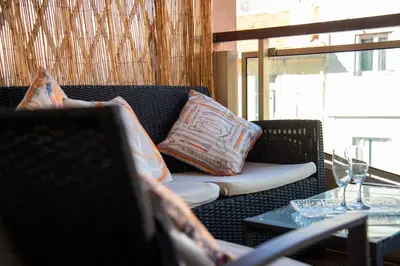 a wicker couch with pillows on top of it at Le Charme YourHostHelper in Cannes